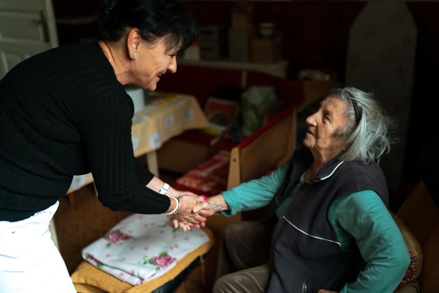 Pflegekraft begrüßt eine ältere Dame herzlich bei einem ersten Hausbesuch