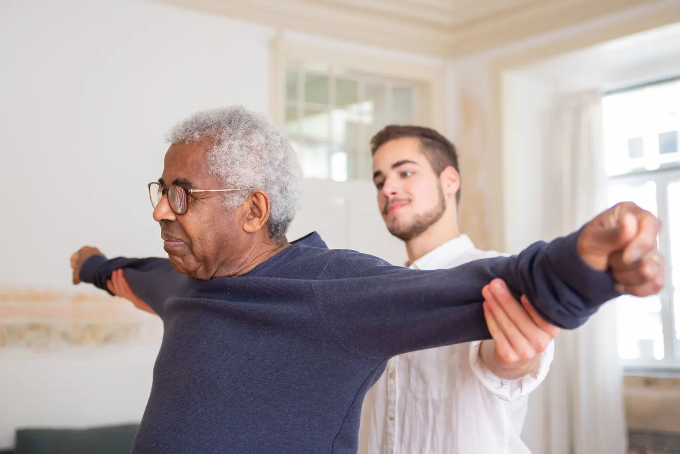 Physiotherapeutin übt mit einem Senior sicheres Gehen